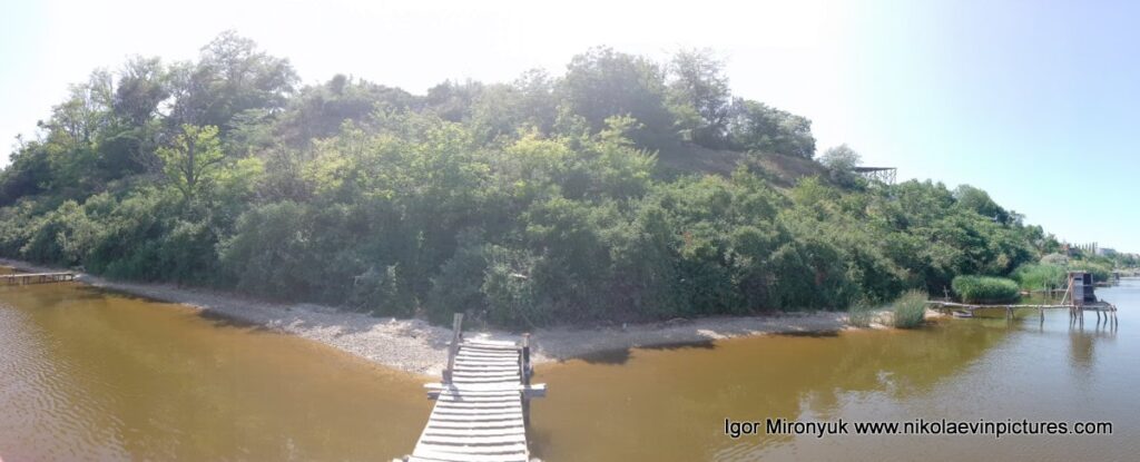 Это фотография показывает длинный рыбацкий мостик, узкую береговую полосу и много-много деревьев, словно это какие-то джунгли.