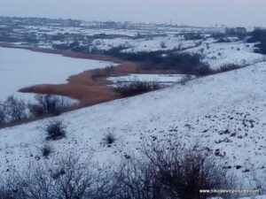 Замёрзла река, протекающая мимо Воскресенска, пригорода Николаева. Также видно камыши с акваториями внутри них.