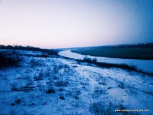 Замёрзла река, протекающая мимо Воскресенска, пригорода Николаева. Также на фото видно камыши. На дворе сумерки.